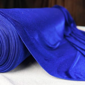 A roll of shiny blue fabric is displayed on a white surface.