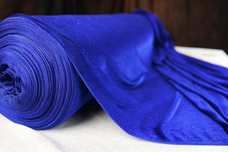 A roll of shiny blue fabric is displayed on a white surface.
