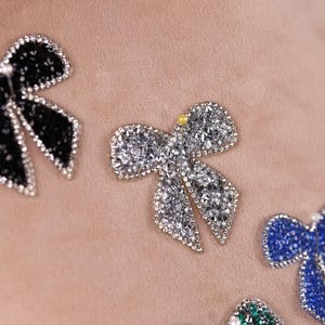 a close-up view of several decorative bows made of glittery materials, such as rhinestones or sequins, attached to a surface.