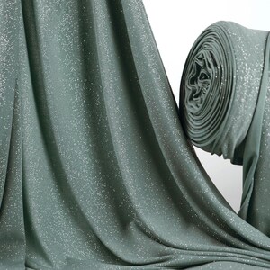 a close-up view of a green fabric with a sparkling texture, possibly a sheer or sheer-like material.