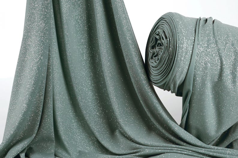 a close-up view of a green fabric with a sparkling texture, possibly a sheer or sheer-like material.