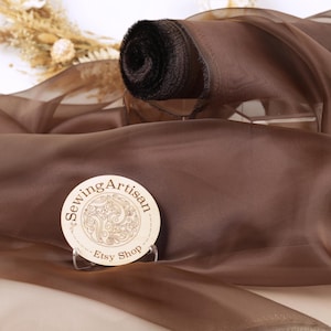 Tessuto in organza marrone cristallizzata: un tessuto trasparente e scintillante, perfetto per decorare abiti.