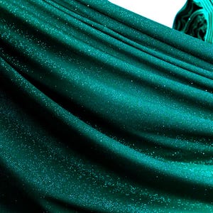 a close-up view of a shiny, turquoise-colored fabric with a sparkling texture, creating a visually striking and vibrant appearance.