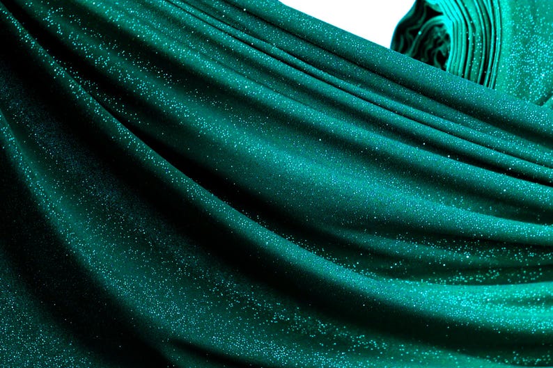 a close-up view of a shiny, turquoise-colored fabric with a sparkling texture, creating a visually striking and vibrant appearance.