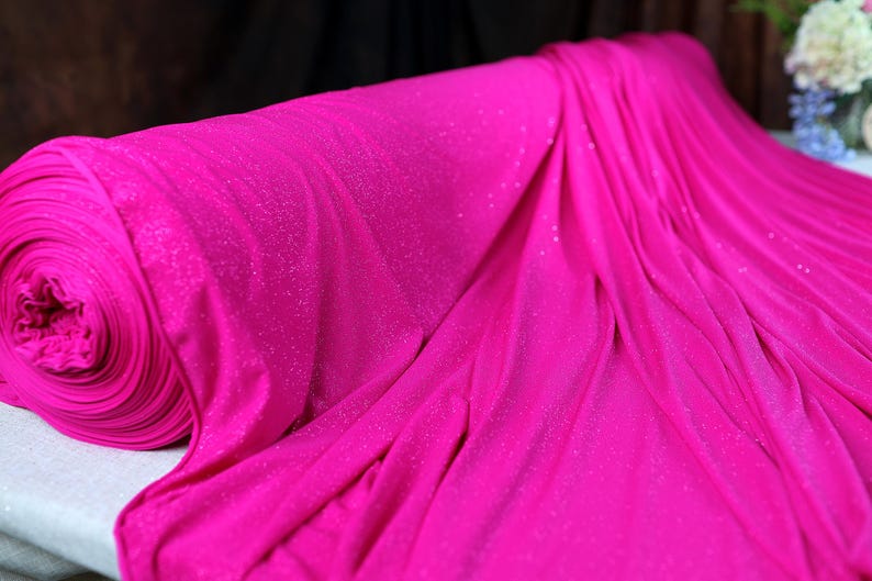 A close-up view of a vibrant pink fabric with sparkles, possibly a sheer or sheer-like material.