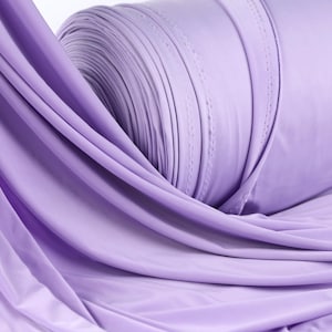 A close-up view of a roll of lavender fabric, with its soft, flowing texture and vibrant color.