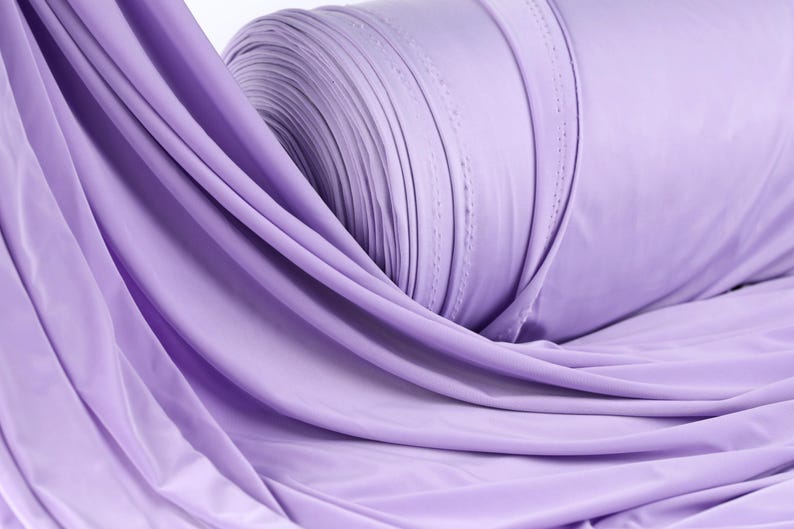 A close-up view of a roll of lavender fabric, with its soft, flowing texture and vibrant color.