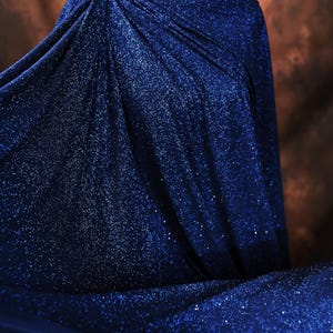 a close-up view of a shiny, blue fabric with a sparkly texture, creating a visually striking contrast against the brown background.