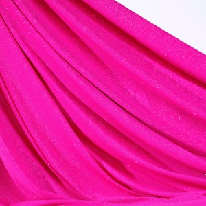 The image is a close-up of a bright pink fabric with a shiny, sparkly texture.