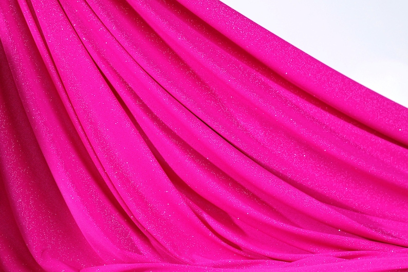 The image is a close-up of a bright pink fabric with a shiny, sparkly texture.