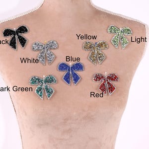A mannequin torso with seven different colored and patterned rhinestone or crystal-like embellishments attached to it, each labeled with a color and pattern.