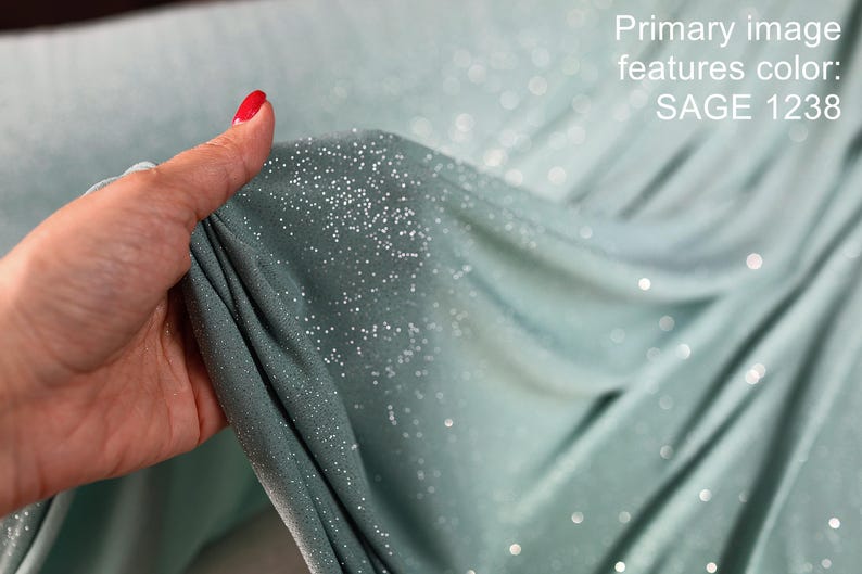 A hand holding a piece of fabric with a glittery texture, and the background is a blurred green color.