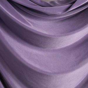 a close-up view of a purple fabric, possibly a curtain or garment, with a soft, flowing texture.