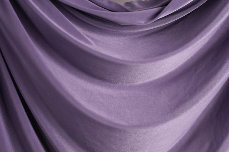 a close-up view of a purple fabric, possibly a curtain or garment, with a soft, flowing texture.