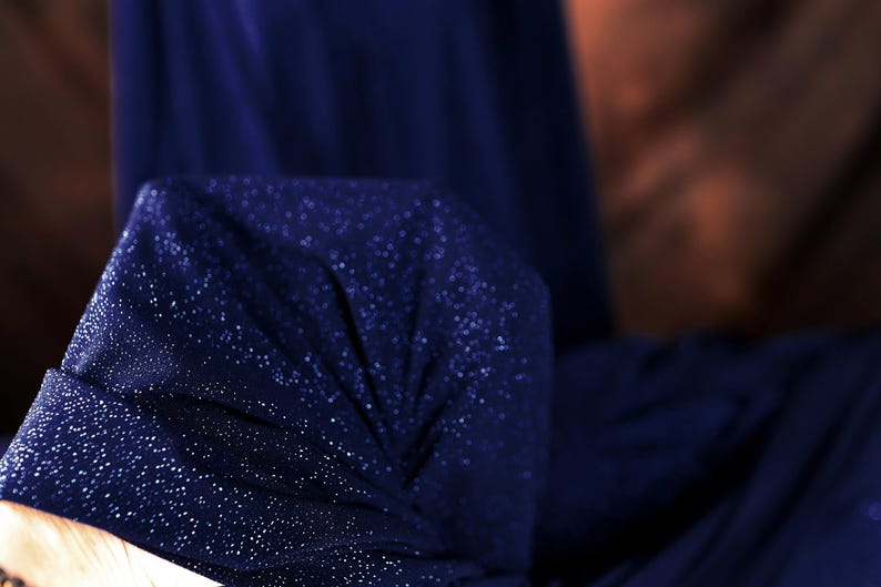 a close-up view of a dark blue fabric with a sparkling texture, possibly a piece of clothing or a decorative item.
