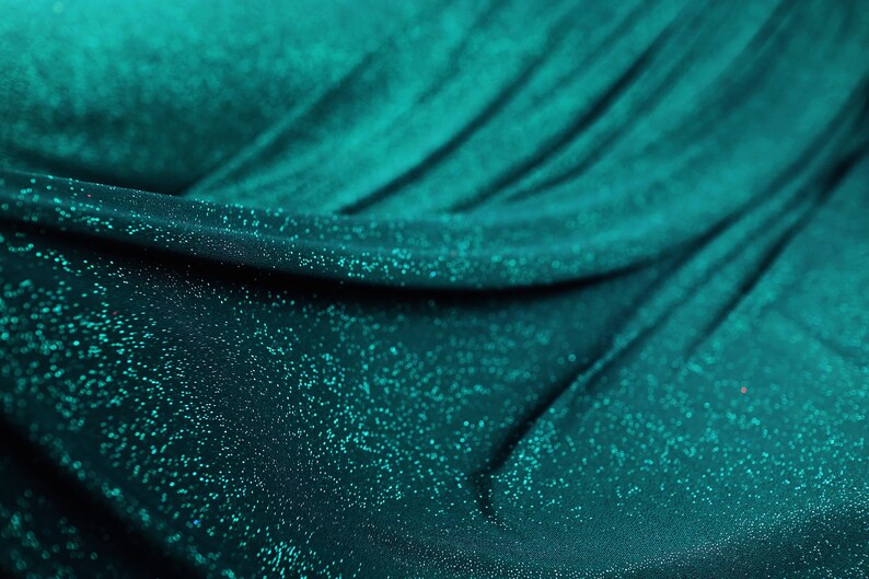 a close-up view of a shiny, turquoise-colored fabric with a glittery texture, creating a sparkling effect.