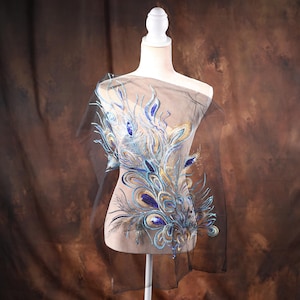 May include: A blue and gold peacock feather design embroidered on a sheer fabric. The design is intricate and detailed, with realistic feathers and a shimmering gold finish.