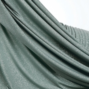 A close-up view of a shiny, metallic green fabric with a textured, crumpled appearance.