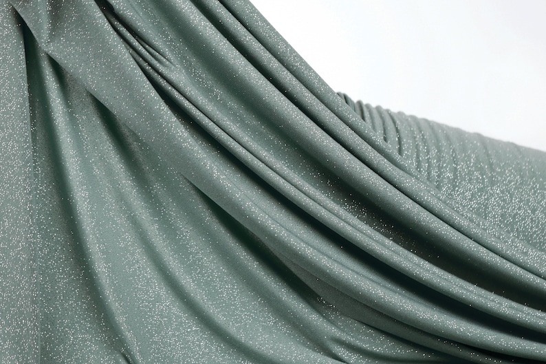 A close-up view of a shiny, metallic green fabric with a textured, crumpled appearance.