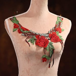 Puede incluir: Aplique de encaje floral rojo y verde con un diseño delicado. El aplique presenta un grupo de rosas rojas con hojas y enredaderas verdes. El encaje es perfecto para agregar un toque de elegancia a cualquier proyecto.