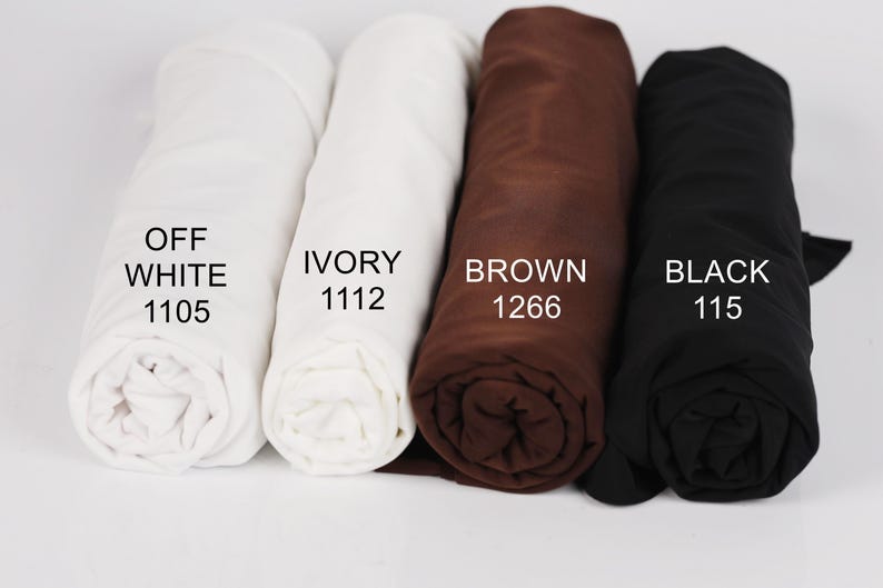 four rolled-up fabric swatches in different colors: white, ivory, brown, and black.