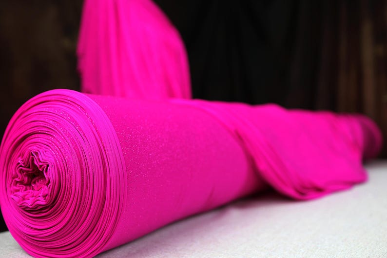 A close-up image of a bright pink fabric roll, possibly a piece of clothing or textile, resting on a surface.