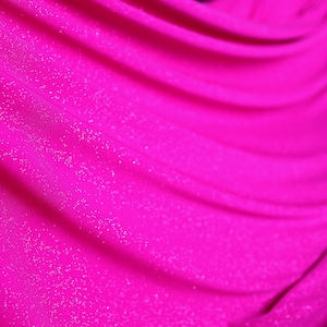 A close-up view of a shiny, sparkly pink fabric, possibly a sheer or sheer-like material.