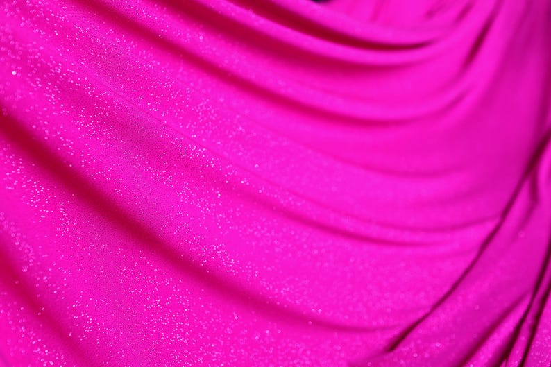 A close-up view of a shiny, sparkly pink fabric, possibly a sheer or sheer-like material.
