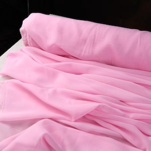 A close-up view of a pink fabric, possibly chiffon, with a crumpled texture.