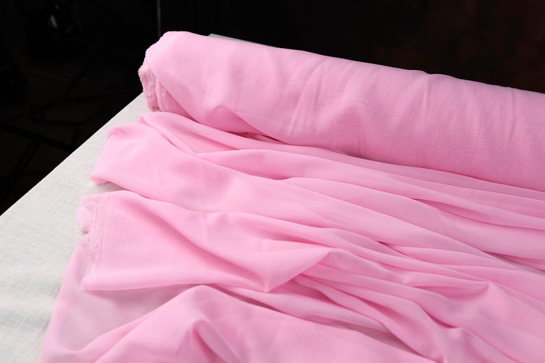 A close-up view of a pink fabric, possibly chiffon, with a crumpled texture.