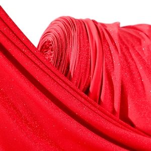 A close-up view of a red fabric with a shiny, sparkly texture.
