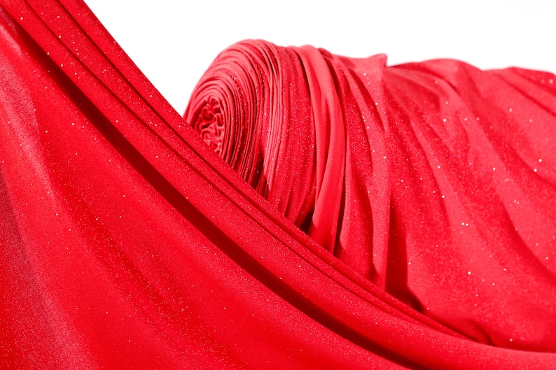 A close-up view of a red fabric with a shiny, sparkly texture.