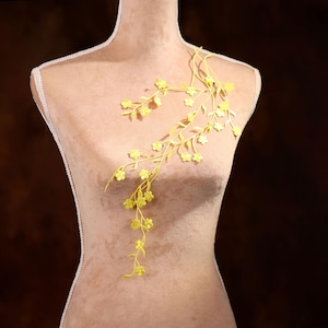 May include: A yellow floral applique with delicate branches and small flowers, ideal for adding a touch of elegance to clothing or crafts.