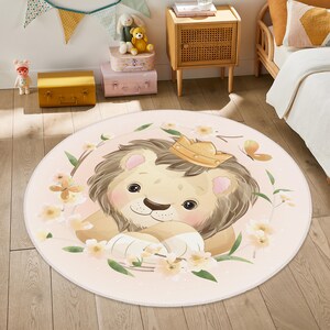 May include: A pink round rug with a cartoon lion wearing a gold crown. The lion is surrounded by pink and white flowers and green leaves.