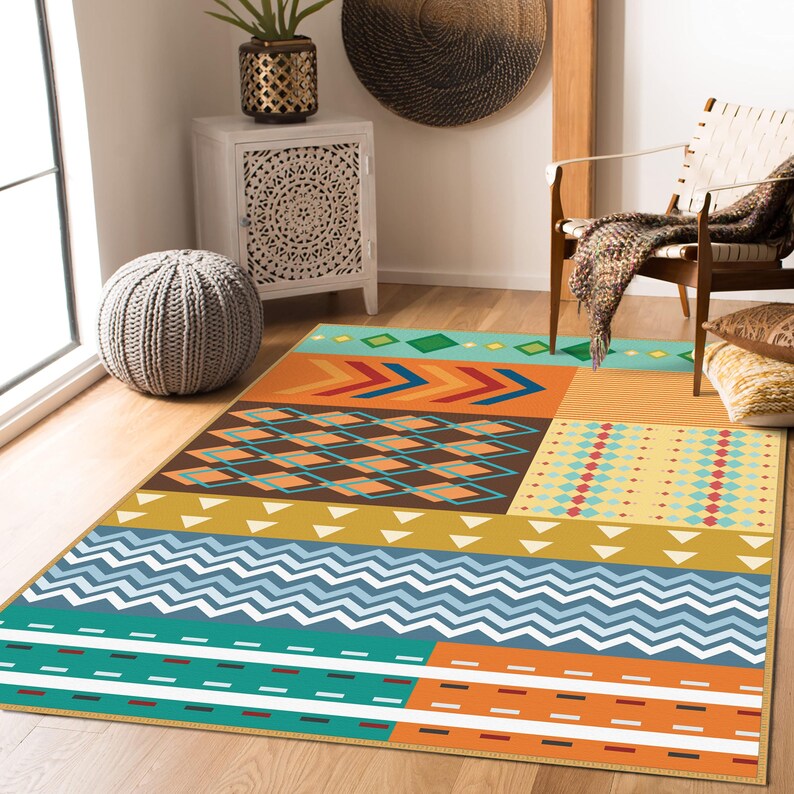 May include: A rectangular area rug featuring a multi-colored geometric pattern. The design includes sections of teal, orange, yellow, and brown, with repeating motifs such as chevrons, diamonds, zigzags, and horizontal stripes across the surface.