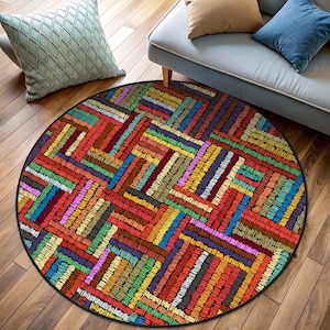 Może przedstawiać: Okrągły, kolorowy dywan z geometrycznym wzorem z nakładających się prostokątów w odcieniach czerwieni, pomarańczy, żółci, zieleni, błękitu, fioletu i brązu. Dywan ma czarną obwódkę.