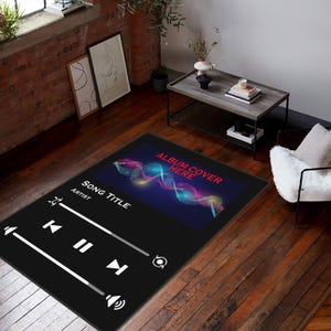 Puede incluir: Alfombra rectangular negra con un diseño de interfaz de reproductor de música. La alfombra presenta controles de reproducción blancos, un icono de volumen y el texto "SONG TITLE", "ARTIST" y "ALBUM COVER HERE". El área de la portada del álbum tiene un diseño abstracto colorido.