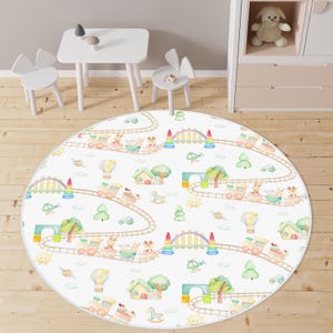May include: A round area rug featuring a repeating watercolor pattern of trains on tracks, hot air balloons, small houses, trees, and animals including giraffes and rabbits, set against a white background with a light gray border.