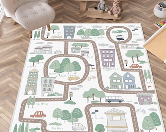 Puede incluir: Una alfombra rectangular con fondo blanco y un diseño impreso de mapa de ciudad. El patrón incluye carreteras marrones sinuosas, varios edificios de varios pisos en tonos grises, azules y morados, árboles verdes, coches y bicicletas.