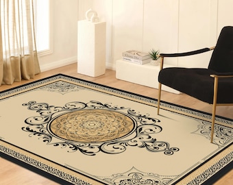 May include: A rectangular area rug featuring a beige background with a central circular mandala pattern in shades of brown and black. The rug is bordered by a black frame with intricate black scrollwork and floral motifs at the corners.