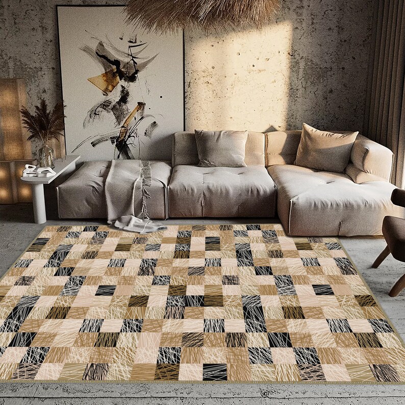 May include: A rectangular rug with a patchwork design in beige, brown, and black. The rug has a repeating pattern of squares with textured, linear details, creating a modern, geometric aesthetic. The rug is placed in a living room setting.