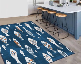 May include: A rectangular area rug featuring a deep blue background with a repeating pattern of stylized fish. The fish are white with orange and dark blue geometric scale details, oriented in various directions across the entire surface.