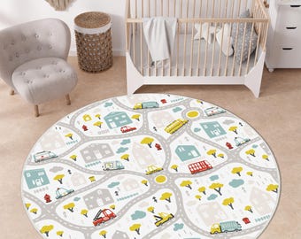 May include: A round area rug featuring a white background with a gray road network, colorful houses in blue and beige, yellow trees, and various vehicles including red fire trucks, yellow school buses, and ambulances.