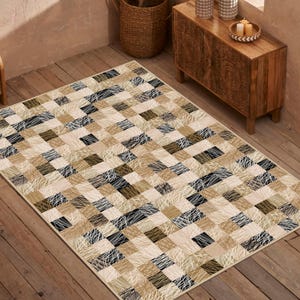 May include: Rectangular rug with a patchwork design. The rug features squares in beige, black, and brown tones, with white linear accents. The rug is placed on a wooden floor, creating a neutral and modern aesthetic.