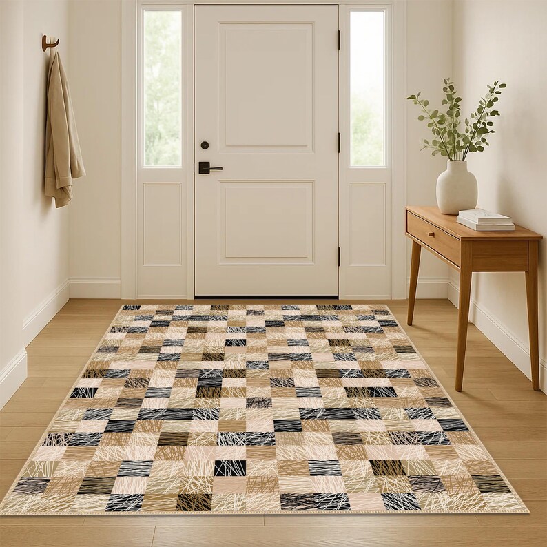 May include: A rectangular rug with a patchwork design. The rug features rectangular blocks in beige, brown, black, and white. Some blocks have a textured, linear design. The rug is placed in a hallway, likely in a home.