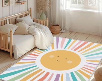 May include: A rectangular area rug featuring a smiling sun design. The sun is yellow with a white background and colorful rainbow rays. The rug is placed on a wooden floor in a bedroom setting.