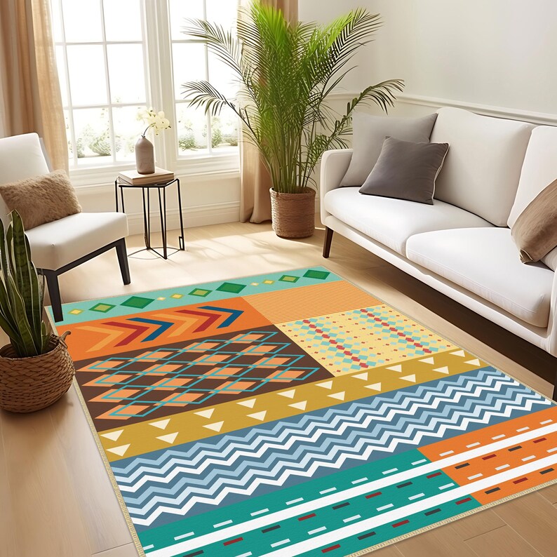 May include: A rectangular area rug featuring a multi-colored geometric pattern. The design includes horizontal bands of teal, orange, and mustard yellow, decorated with various shapes such as diamonds, chevrons, zigzags, and small triangles.