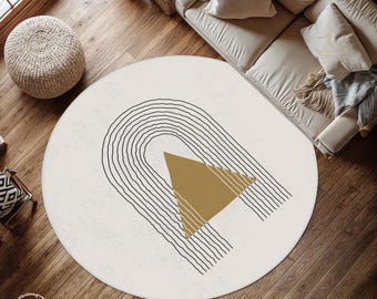 May include: A round area rug with a cream-coloured base featuring a black line art graphic of a series of concentric arches and a solid gold-coloured triangle positioned in the centre of the arch design, creating a geometric pattern on the floor.