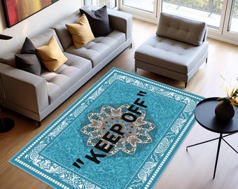 May include: A rectangular area rug featuring a vibrant turquoise background with a central white and gold mandala-style floral pattern. The text "KEEP OFF" is printed in bold black capital letters across the center of the rug design.