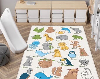 May include: A rectangular area rug featuring a white background with a colorful alphabet-themed animal print. Each letter from A to Z is represented by a cartoon animal illustration, including an alligator, bear, crab, dolphin, elephant, and zebra.